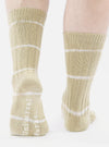 Close-up of a model wearing Dark Sand Tie Dye Knit Slub Sock. The knit socks have white stripes and are on a white background.