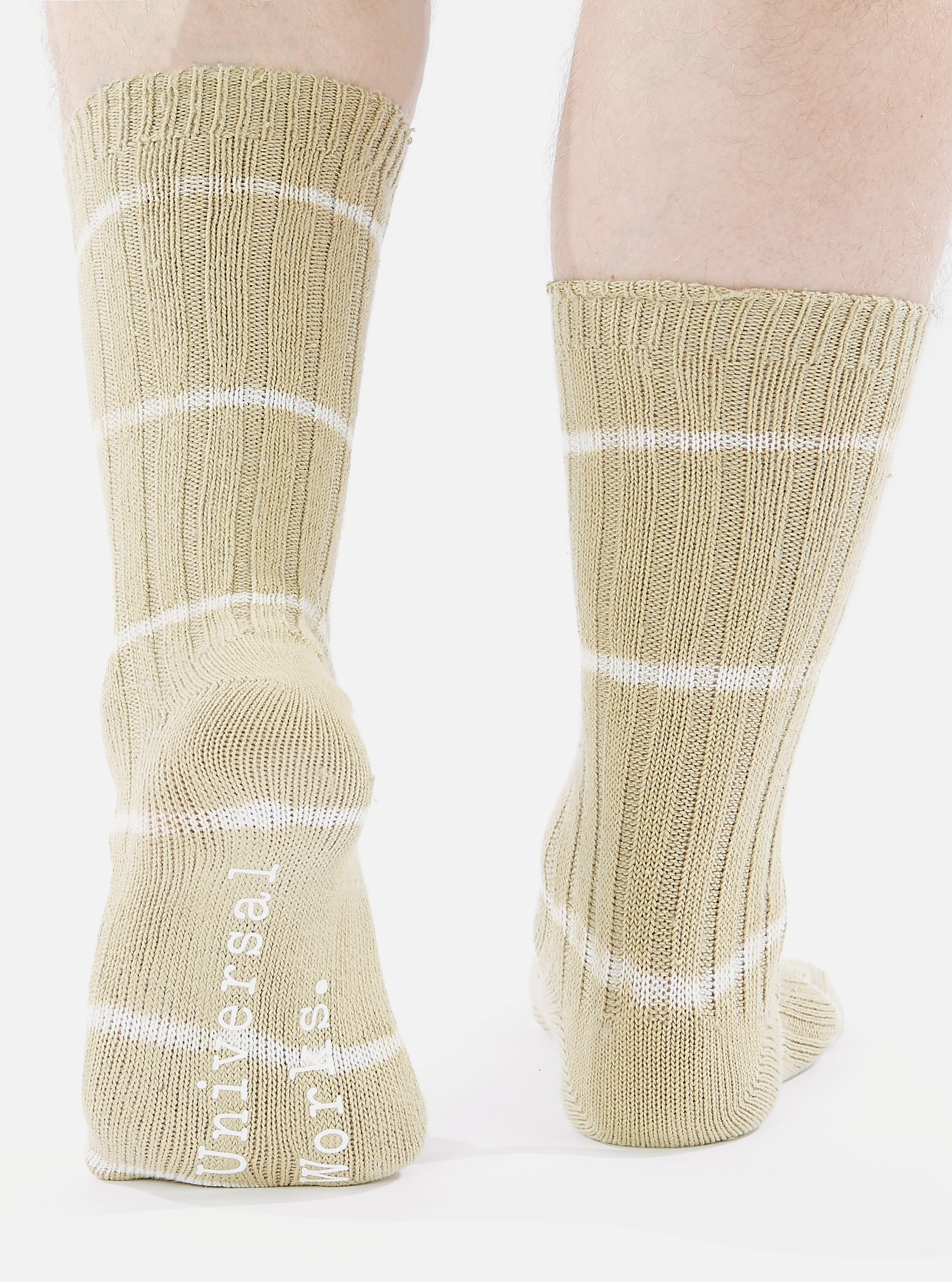 Close-up of a model wearing Dark Sand Tie Dye Knit Slub Sock. The knit socks have white stripes and are on a white background.