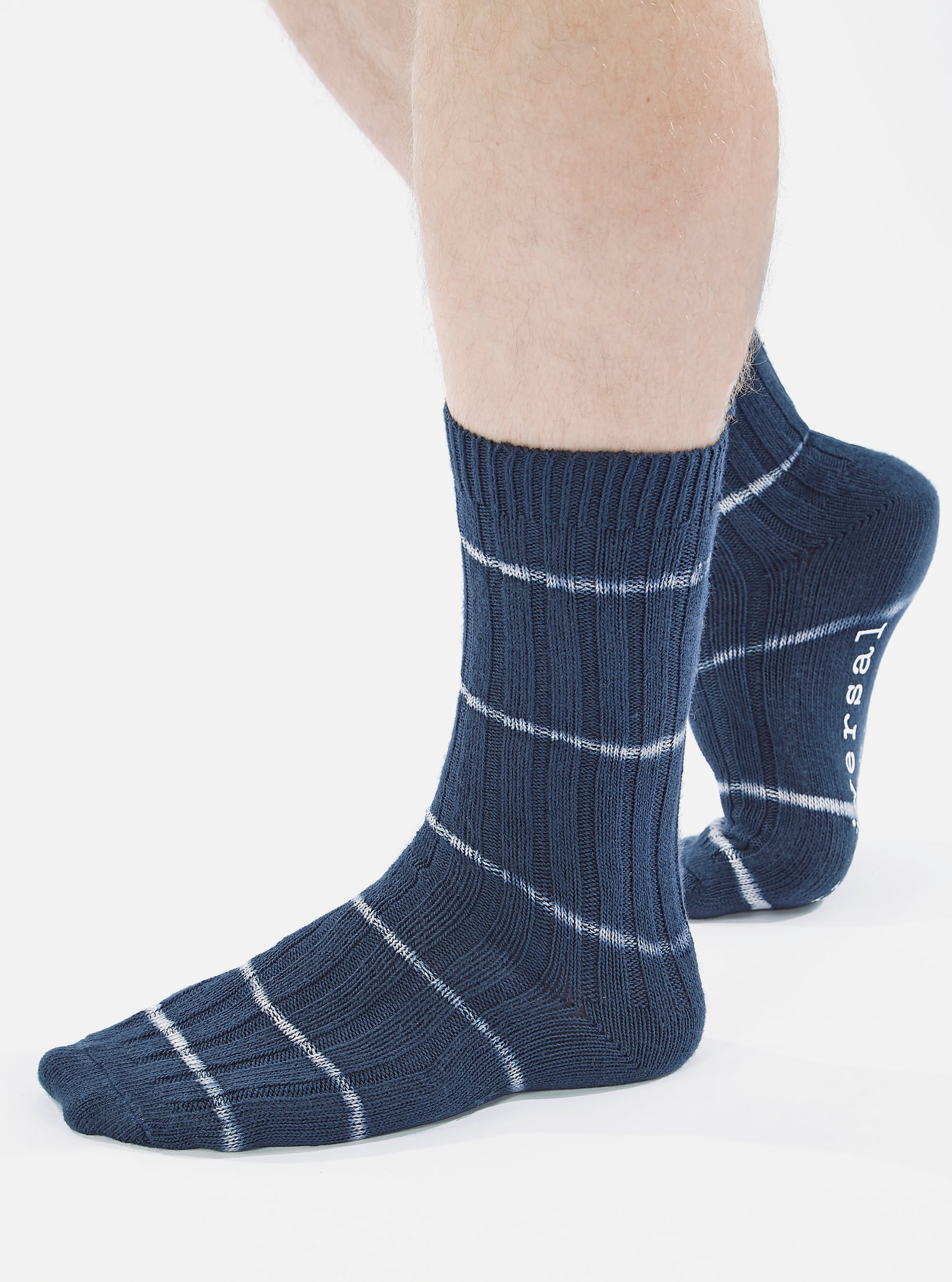 Close-up of a model wearing Navy Tie Dye Knit Slub Sock on a white background. The sock is navy with white stripes and has a ribbed texture.