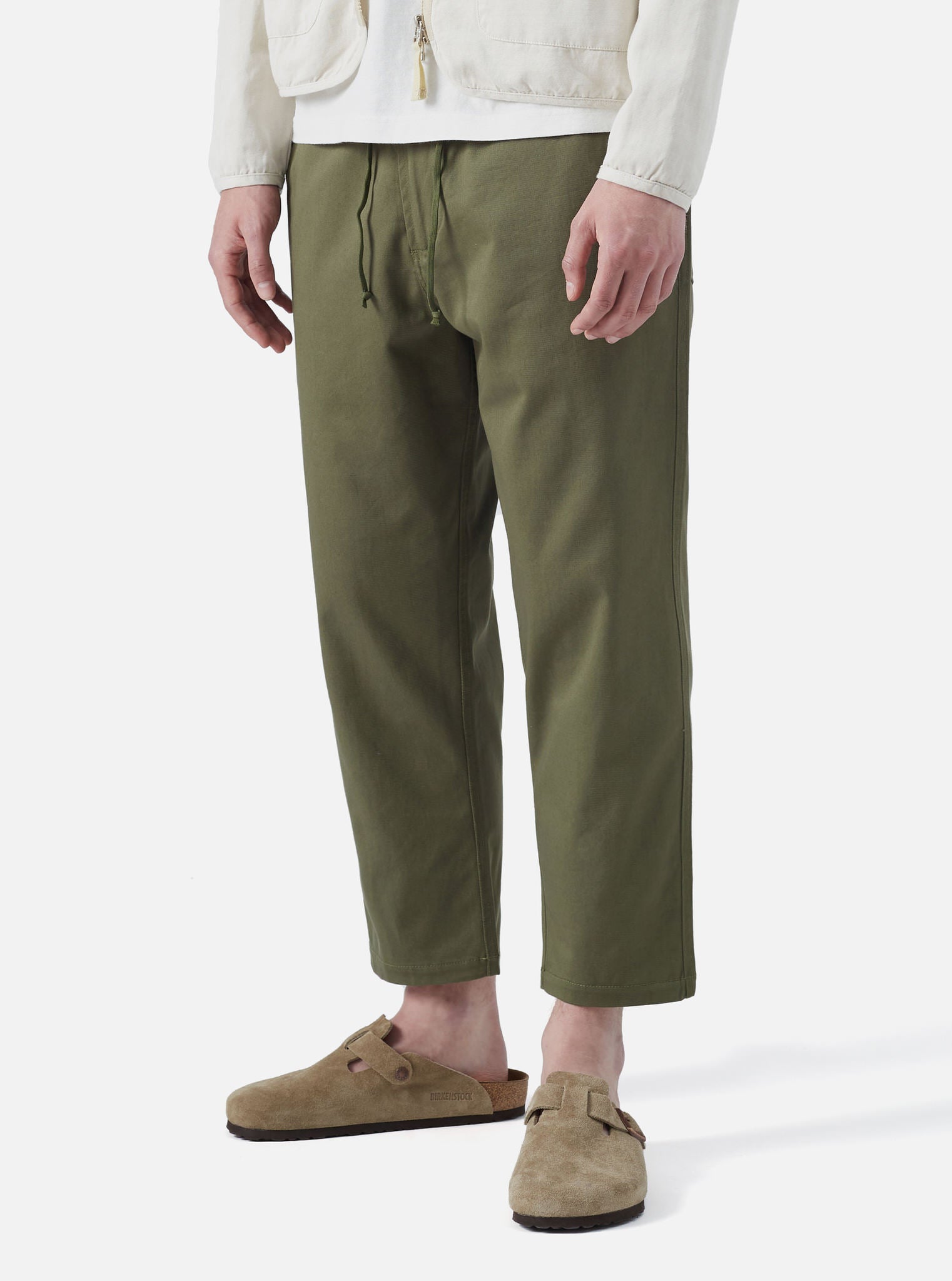 Model wearing Light Olive Twill Hi Water Trouser on a white background. The twill trousers are paired with suede Birkenstocks.