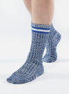 Close-up of a person wearing Navy Cotton Everyday Stripe Sock on a white background. The sock is blue with white stripes at the top.