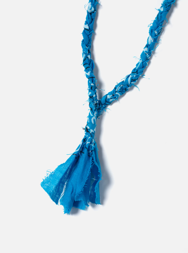 Close-up of the blue Hanami of Rome Bandana Necklace/Bracelet #5 on a white background. The braided fabric necklace has a fringed end.