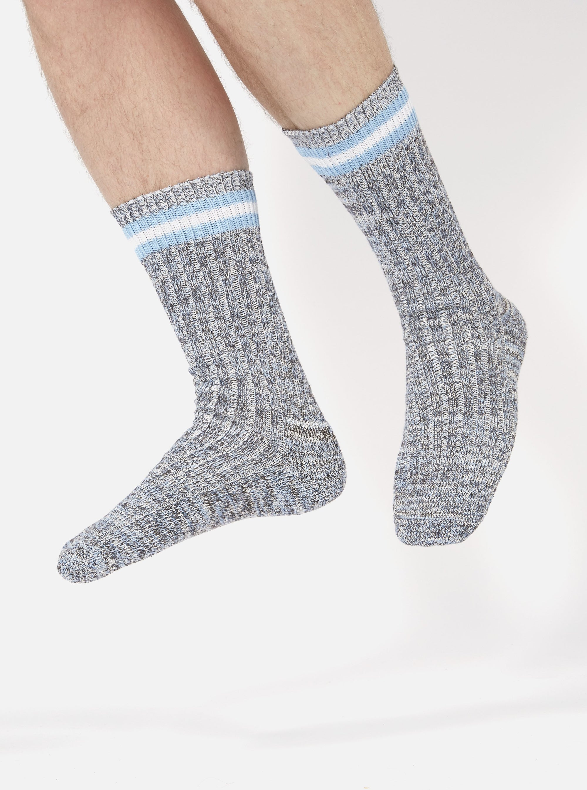 A pair of legs wearing Cornish Blue Cotton Everyday Stripe Sock, made of cotton, with blue and white stripes at the top, on a white background.